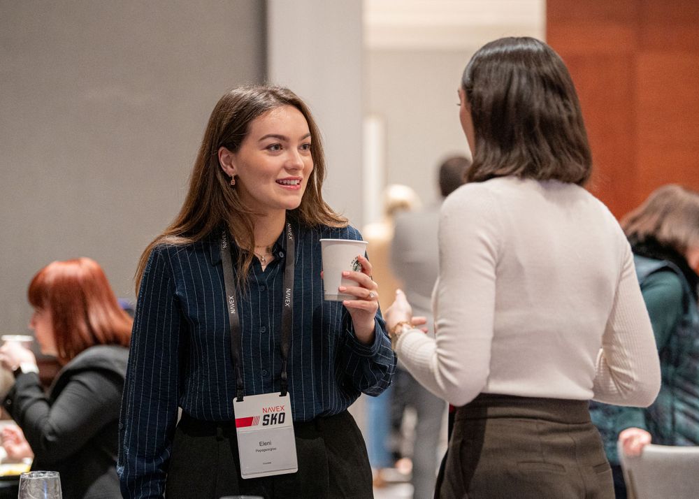 Two people having animated conversation over coffee at indoor conference.