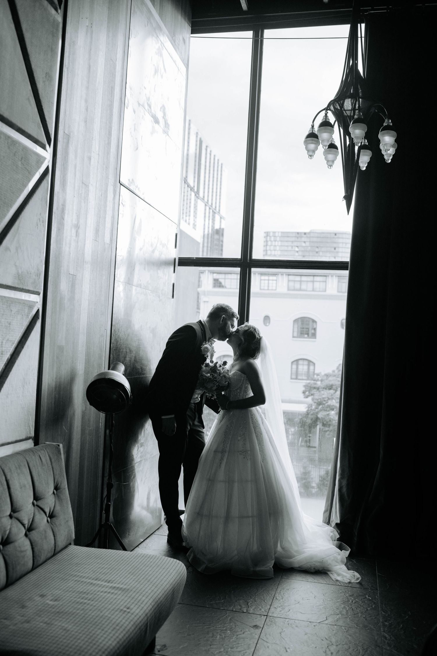 Artistic black and white silhouette of a wedding couple by a window.