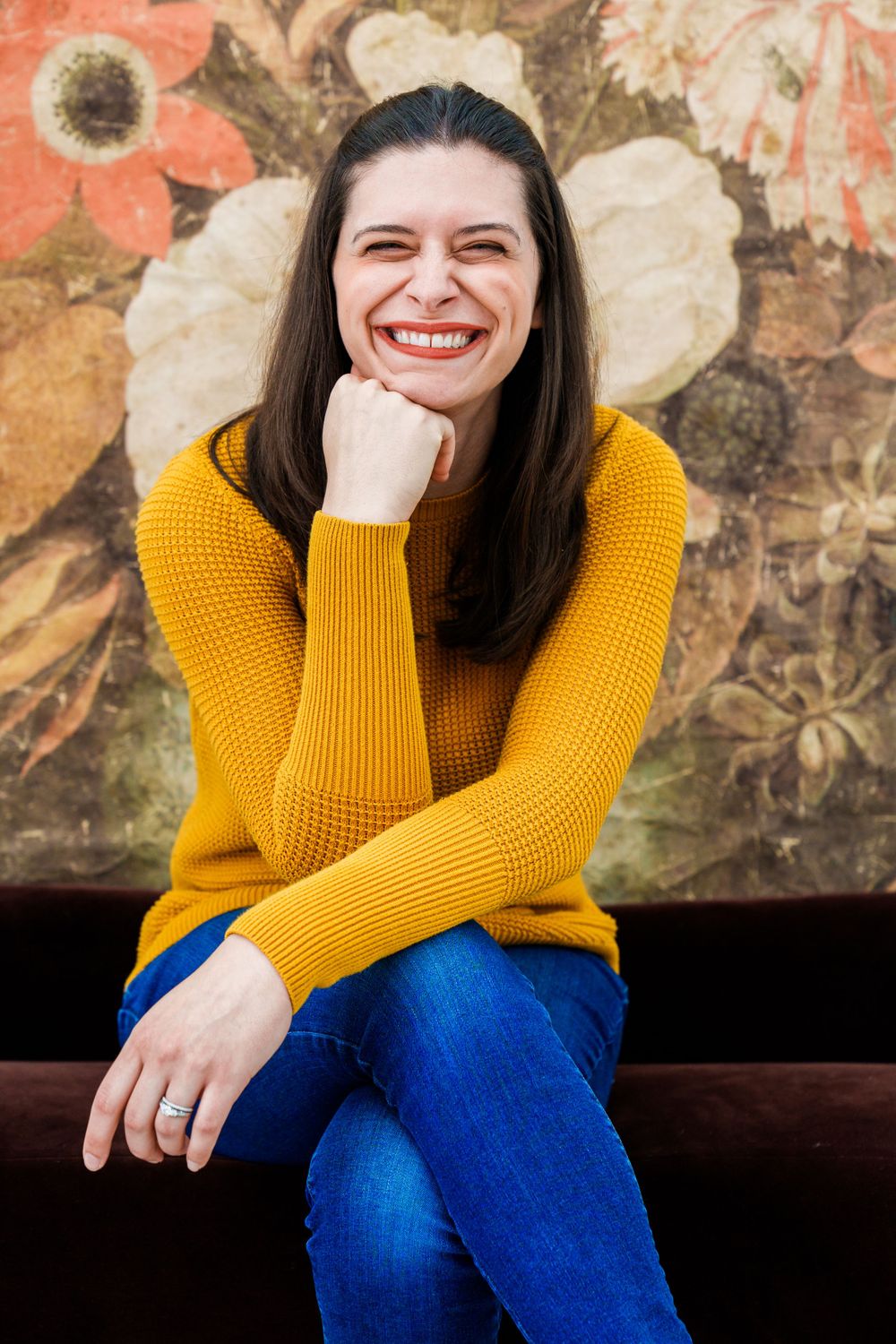 Portrait in yellow sweater against floral backdrop with natural smile.