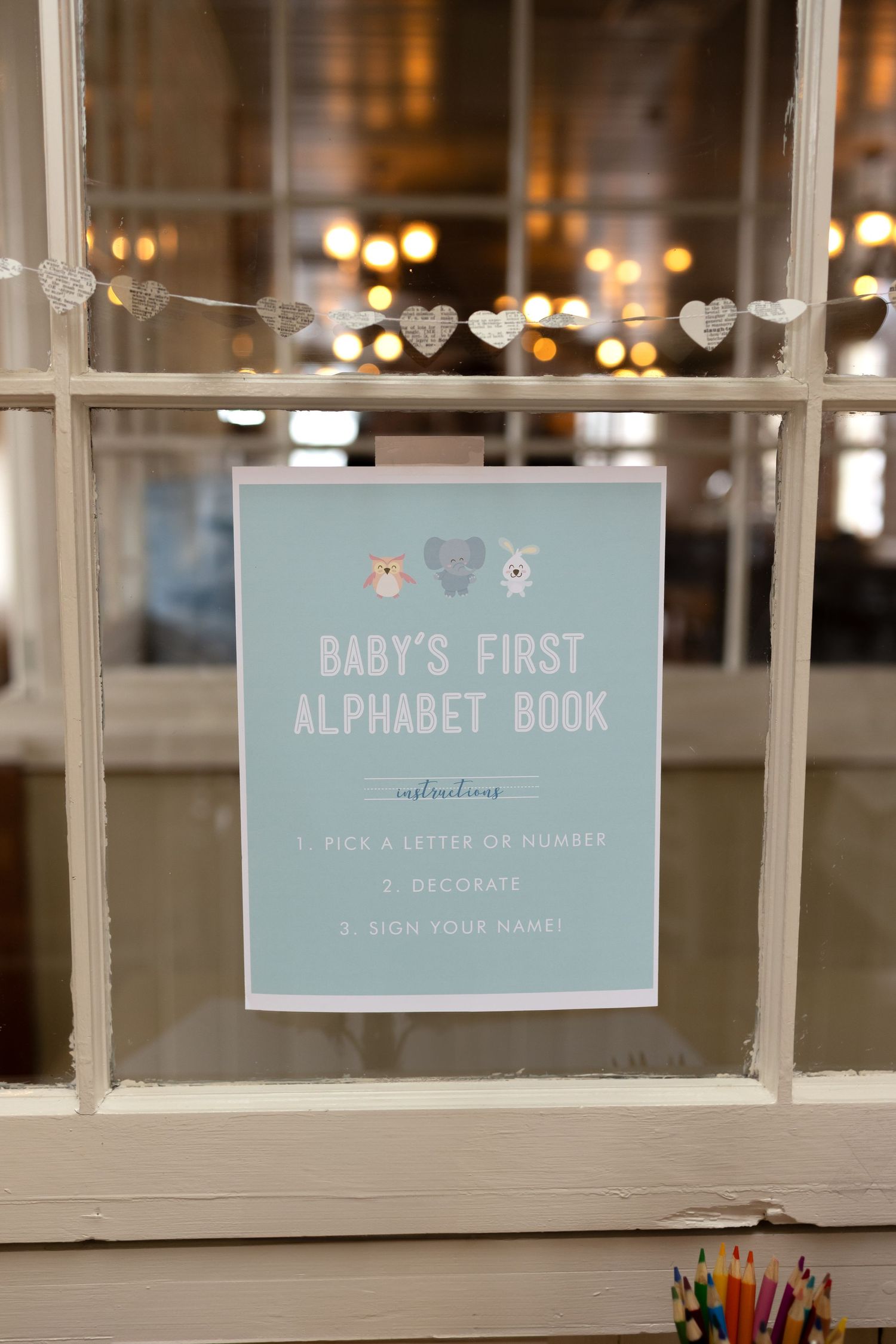Baby shower decorations featuring pale blue signage for a baby's first alphabet book.