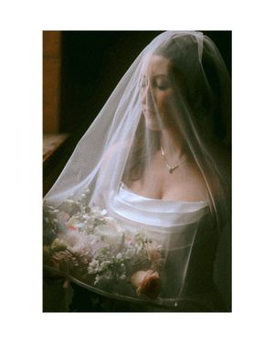 Close-up portrait of bride wearing delicate veil and strapless gown holding a bouquet.