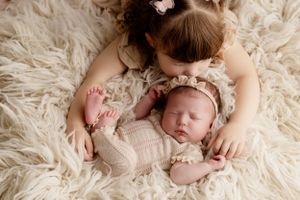 Newborn baby in beige outfit sleeping peacefully on cream fur blanket.
