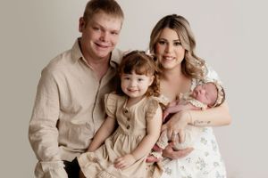 Studio family portrait with young child and newborn in soft neutral colors.