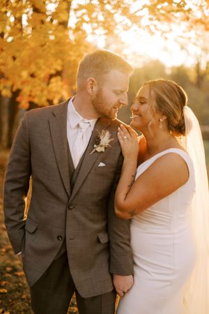 Intimate wedding moment captured during golden hour beneath autumn trees.