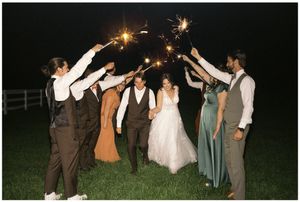 Wedding party holding sparklers at night in celebration with bride and groom.