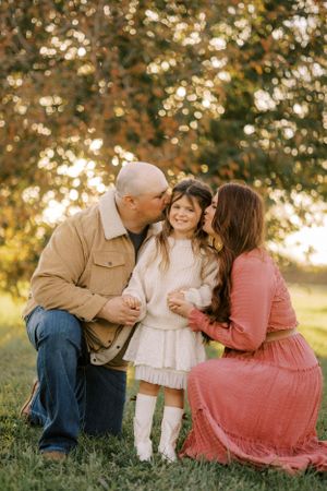 Family shares tender moment together in golden sunset light.