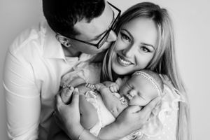 Black and white portrait of parents sharing a joyful moment with their infant child.