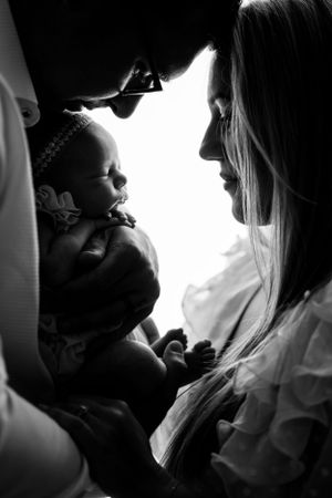 Intimate black and white portrait of tender moments between parent and newborn baby.
