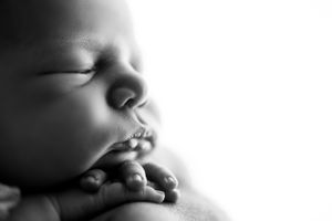 Close-up black and white portrait of a sleeping newborn's peaceful face.