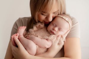 Tender moment between mother and newborn baby showing tiny feet and gentle embrace.