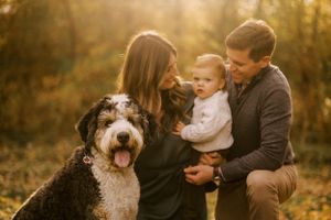 Family portrait in golden sunset light with happy dog outdoors.