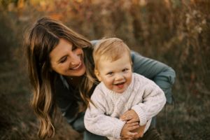 Joyful outdoor portrait capturing laughter between parent and child in autumn setting.