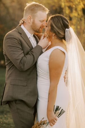 Intimate wedding portrait with sunlit autumn trees in the background.