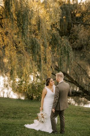 Couple shares a tender moment under drooping willow branches at sunset.