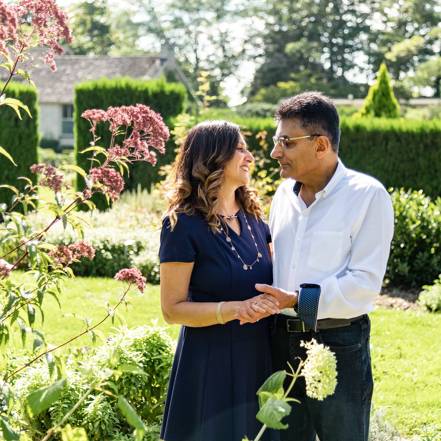 Couple sharing intimate moment among blooming flowers in garden setting.
