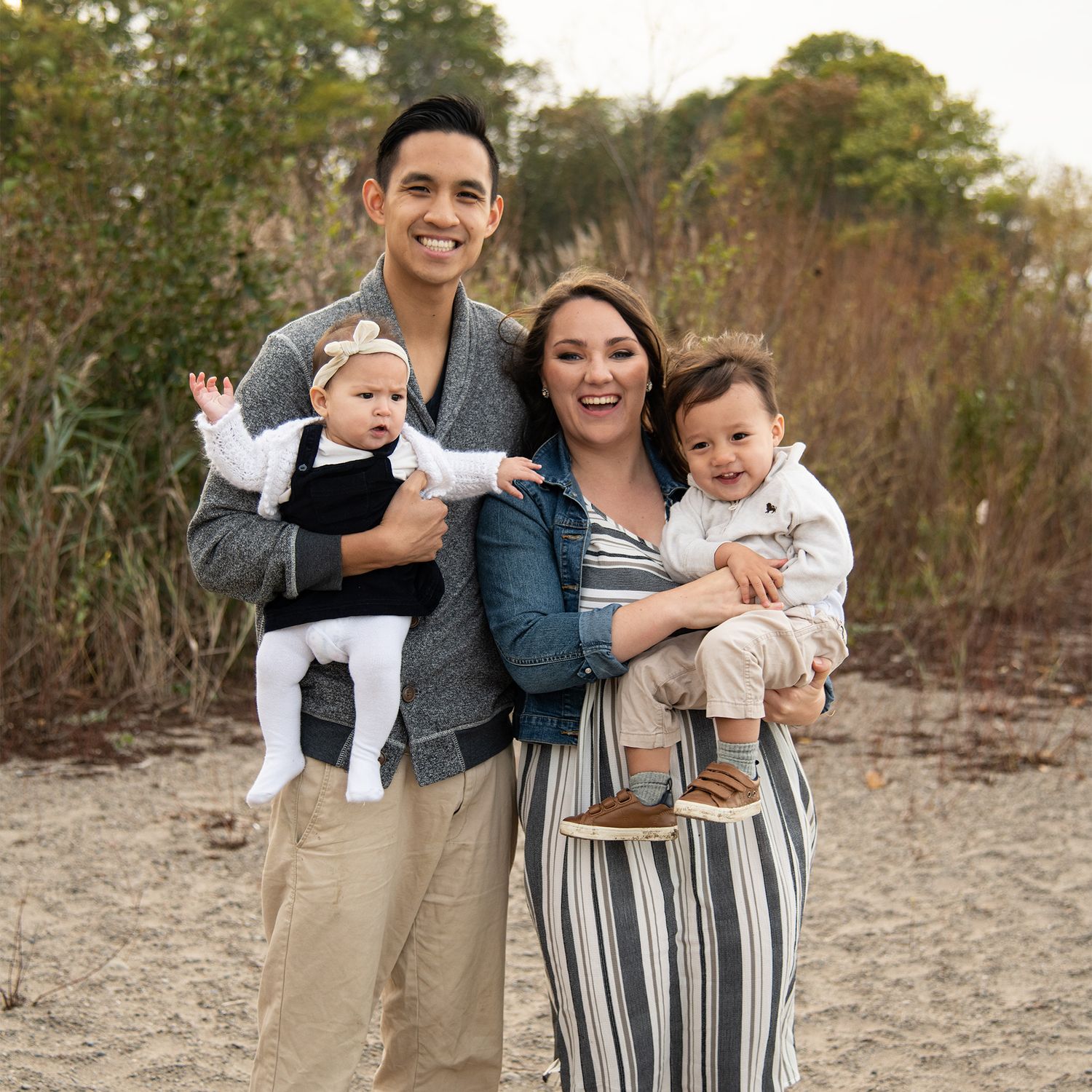 Family laughing together during outdoor photo session at sunset wearing coordinated casual outfits.