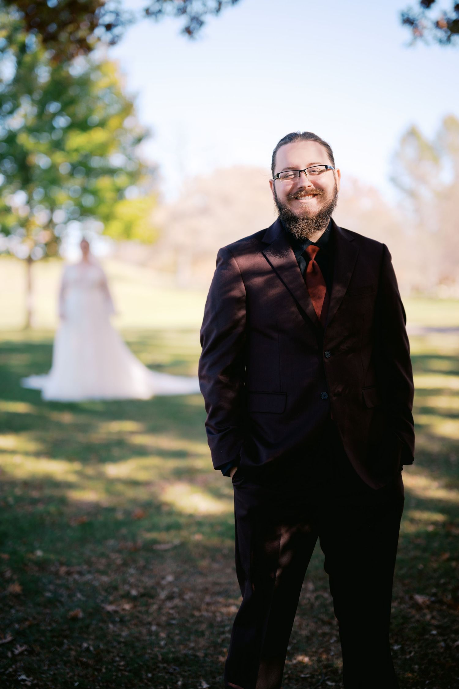 An elegant fall wedding portrait taken outdoors with autumn foliage in the background.
