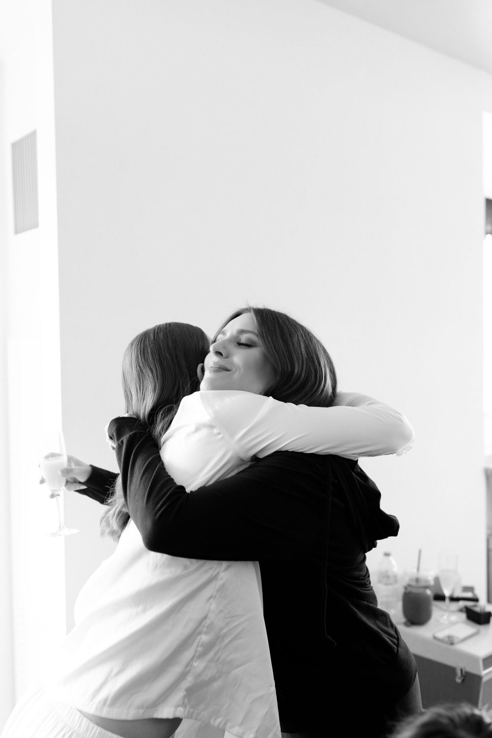 Two people share an emotional embrace in black and white, wearing contrasting black and white clothing.