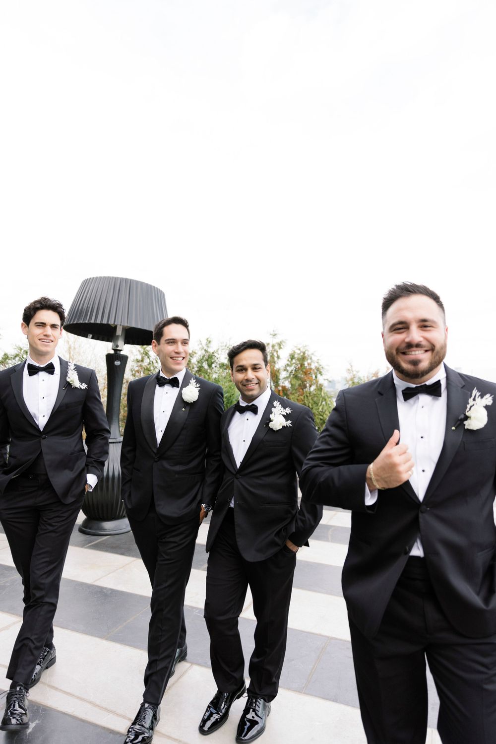 Groomsmen in classic black tuxedos posing together outdoors with boutonnières.