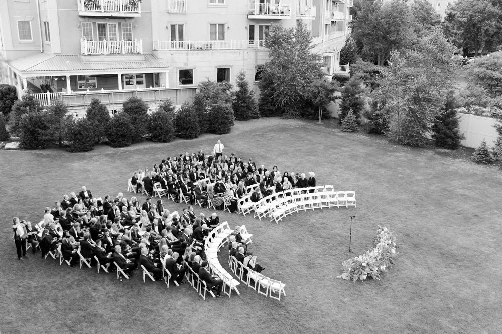 Aerial black and white photograph showing people arranged in a curved formation on a lawn next to apartment buildings.