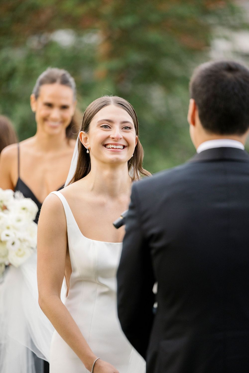 A waterfront wedding moment shows joyful smiles and elegant white gowns.