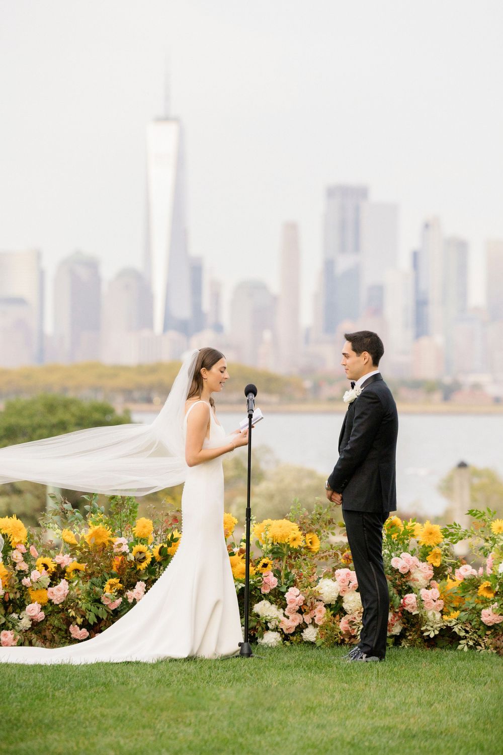 Wedding ceremony setup with NYC skyline backdrop and colorful floral arrangements.