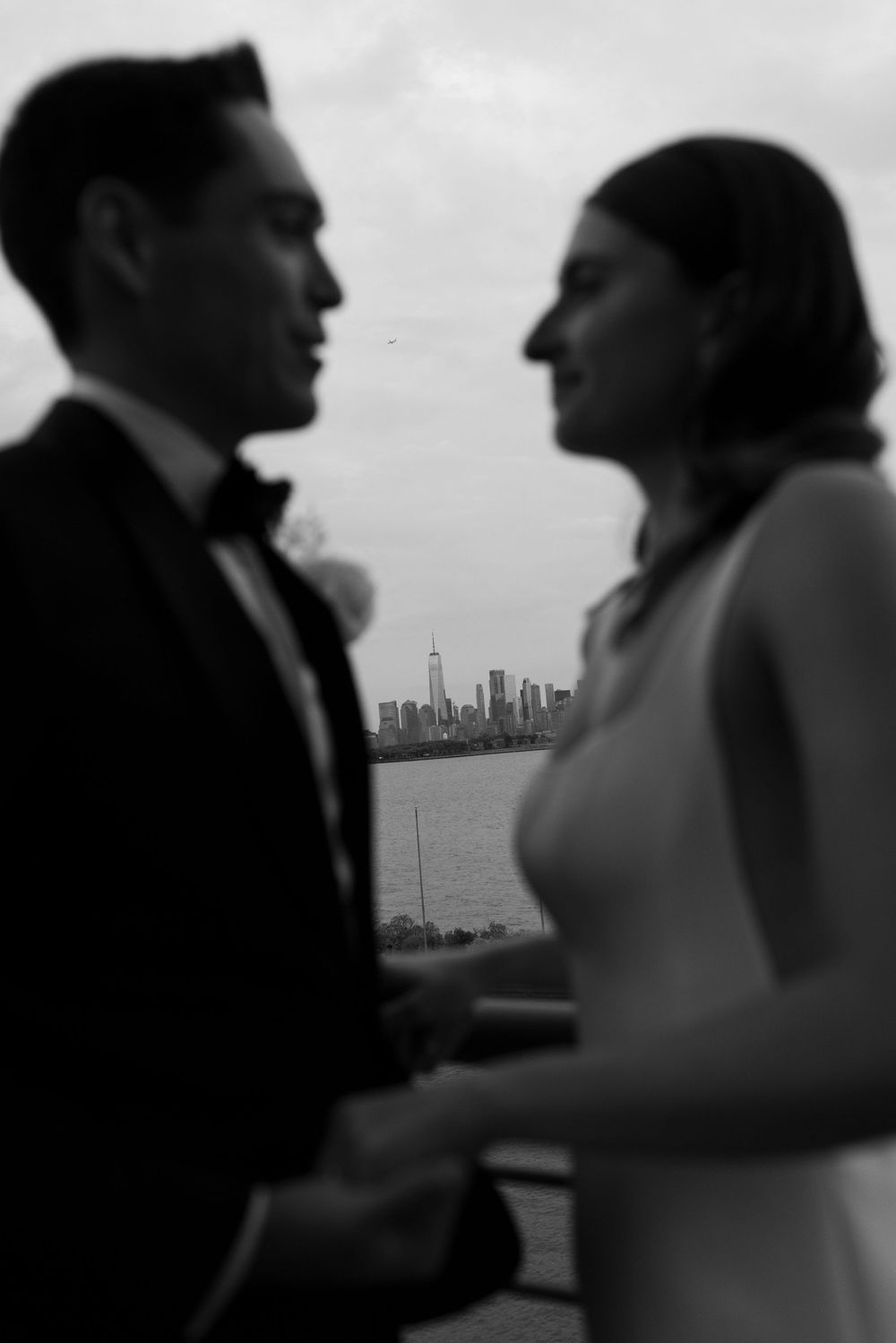A silhouetted couple stands in front of the New York City skyline in a romantic black and white moment.