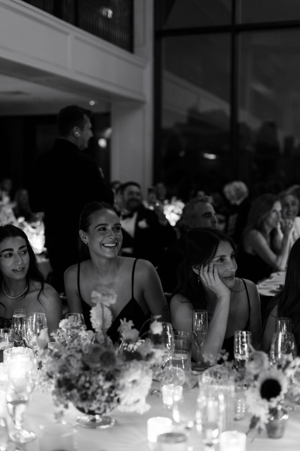 Guests enjoying a candlelit wedding reception dinner with elegant table settings and floral centerpieces.