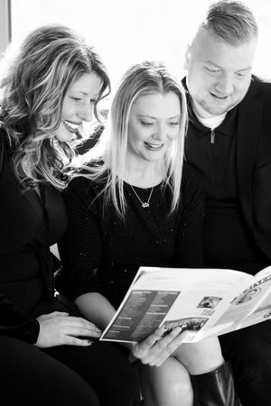 A series of black and white photos show people looking at documents together while sitting and smiling.