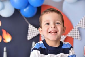 Race car themed party backdrop with blue balloons and checkered flag decorations.