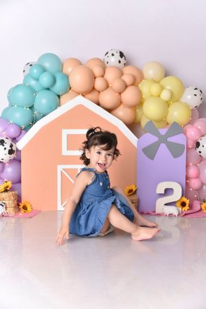 Pastel rainbow balloon garland with colorful house-shaped backdrop for children's photography.
