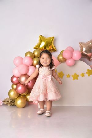 Pink and gold balloon arrangement with star balloons creates elegant birthday photo setting.