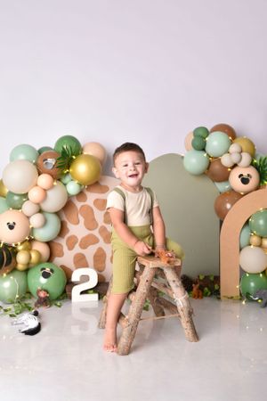 Safari-themed photo backdrop with neutral balloons and giraffe print decorations.