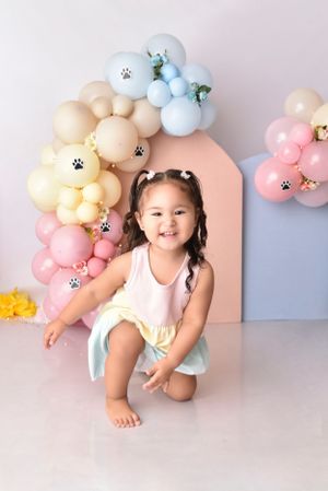 Pastel balloon arch with paw print decorations creates playful birthday photo backdrop.
