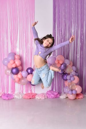 Pink and purple balloon arch with metallic streamers creating a whimsical photo backdrop.
