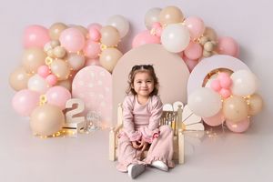 Birthday party backdrop with pink and beige balloon garland arrangement against a light pink wall.