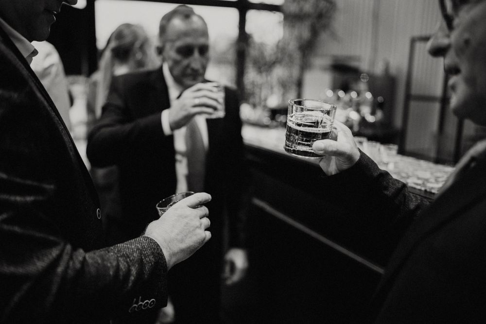 Black and white image of guests toasting with drinks at an elegant reception.