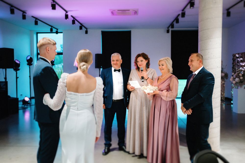 Wedding reception space decorated with purple and blue uplighting and formal attire guests.