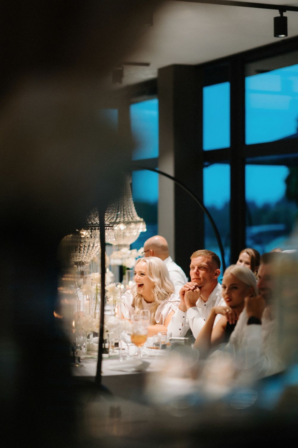 Elegant table settings and crystal chandeliers captured through a creative framing at a wedding reception.
