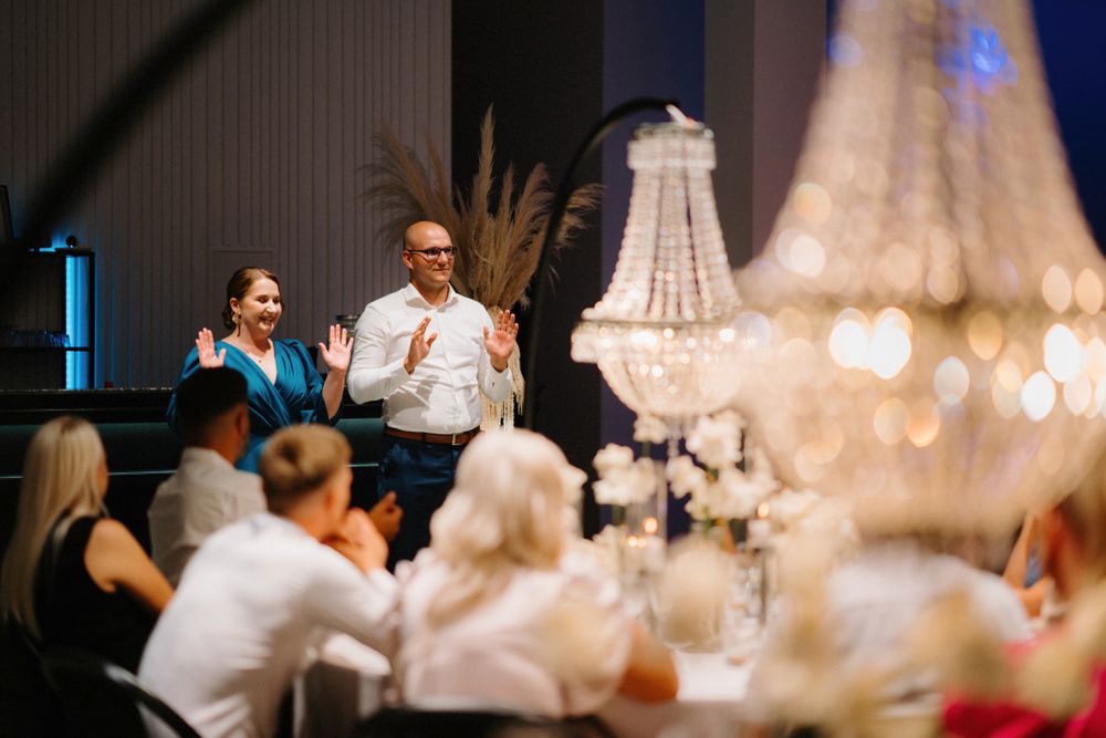 Crystal chandeliers illuminate elegant table settings at an evening wedding reception.