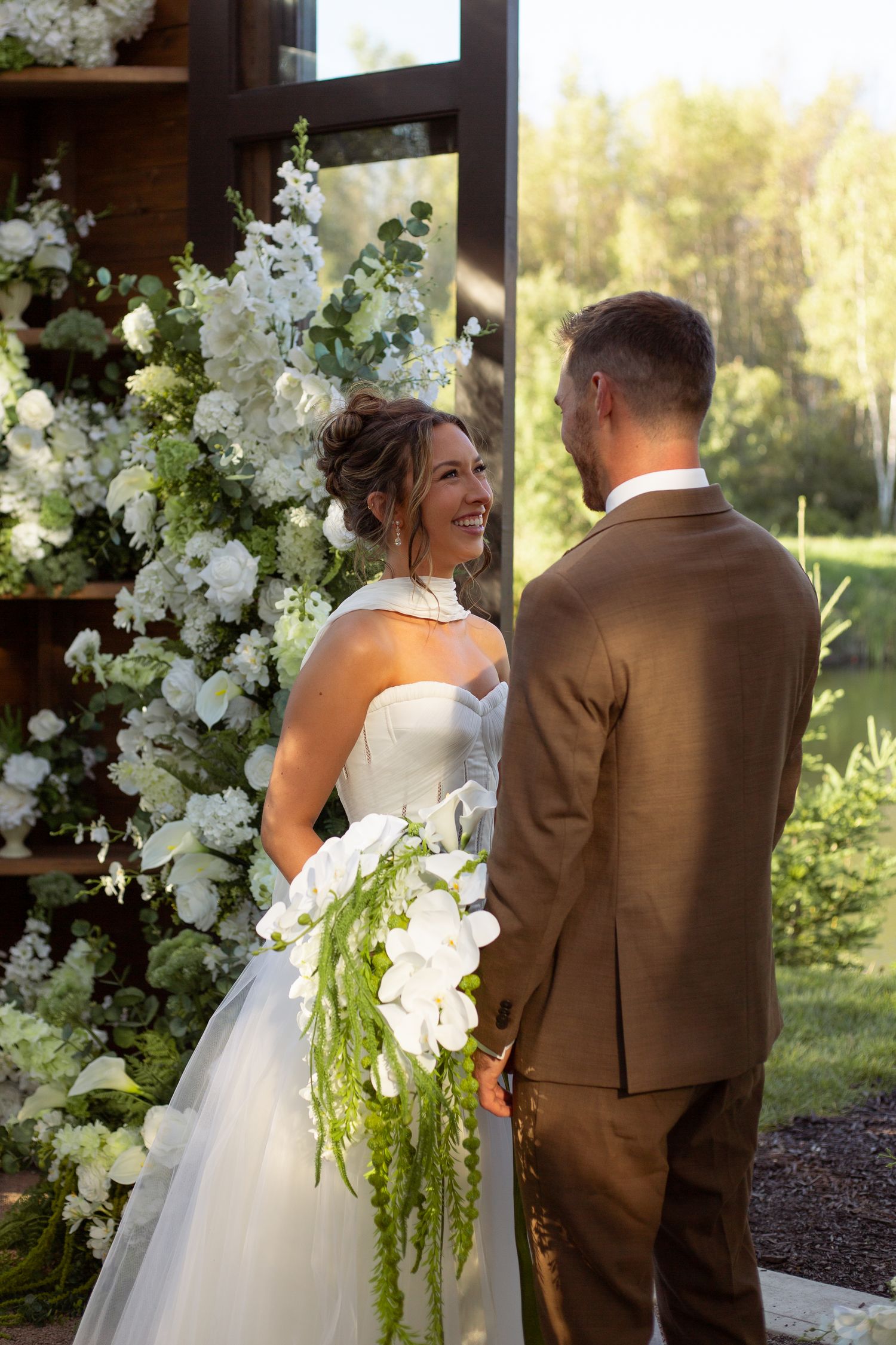 Wedding couple sharing an intimate moment surrounded by white floral arrangements and natural light.
