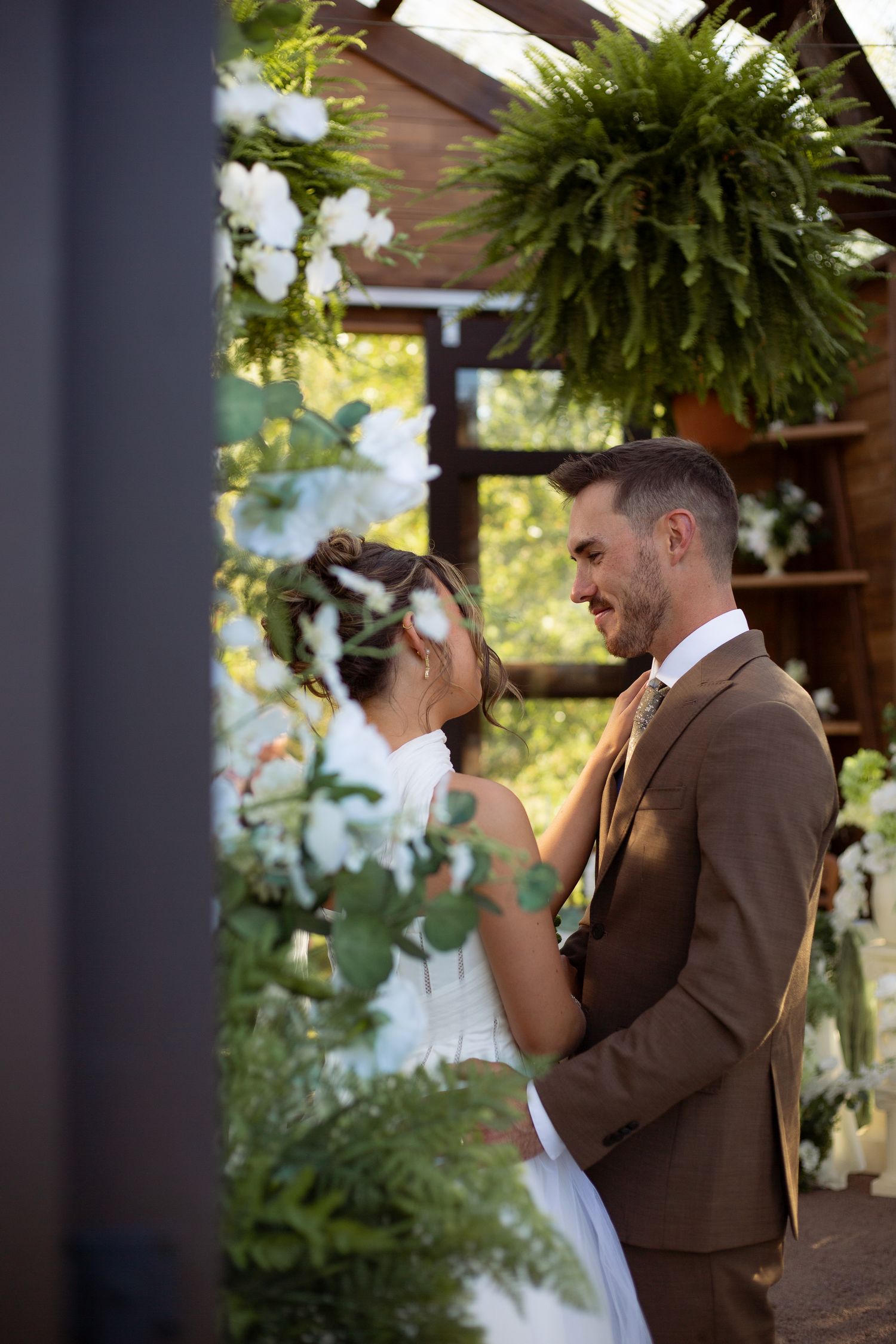 Emotional first look moment between bride and groom on a rustic outdoor porch with hanging plants.
