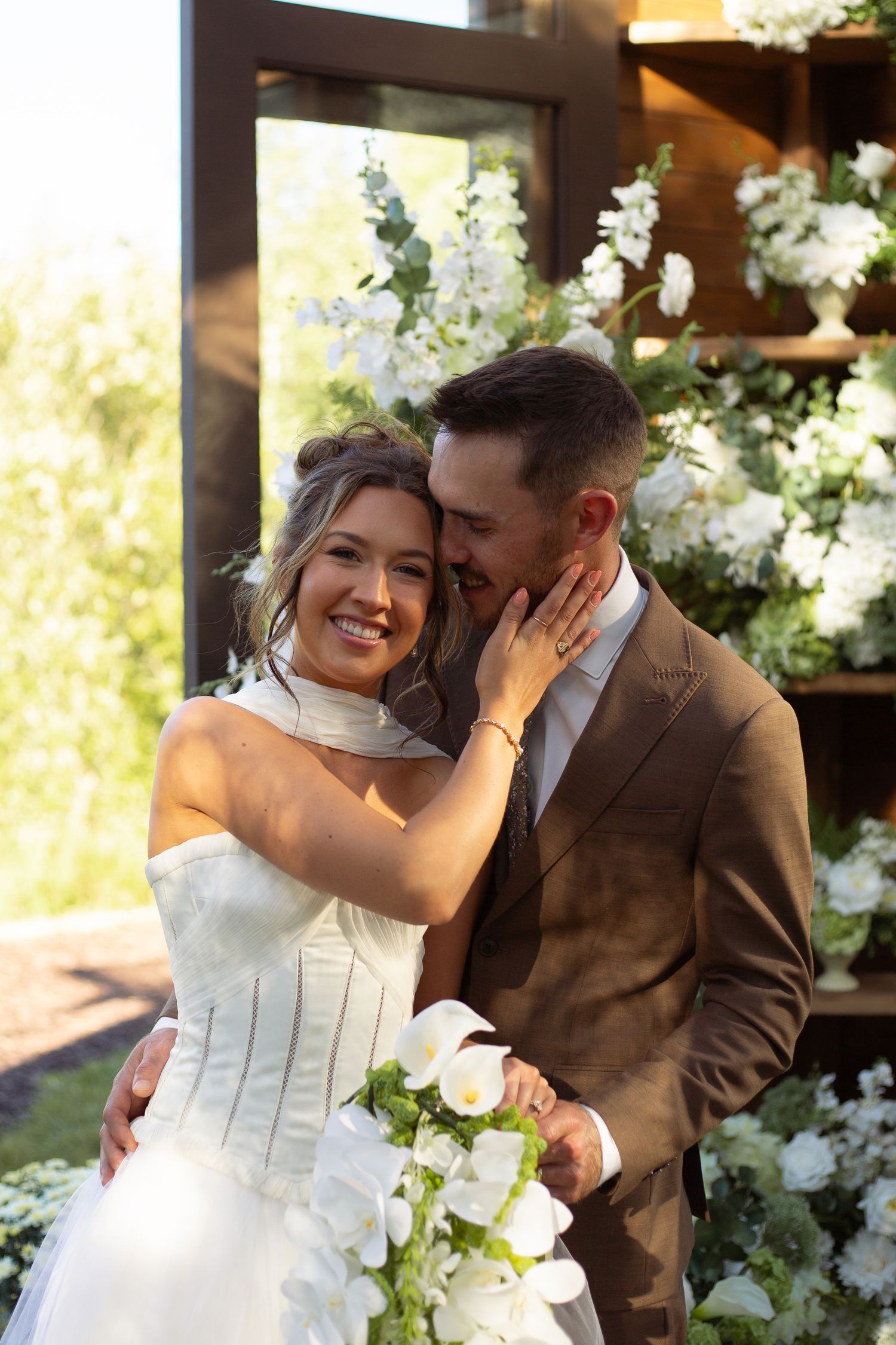 A romantic wedding moment captured in a series of candid photos with white floral decorations in the background.