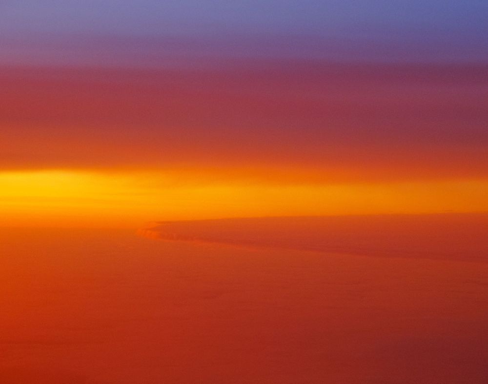 Vibrant sunset sky gradient from deep purple to bright orange over the horizon.
