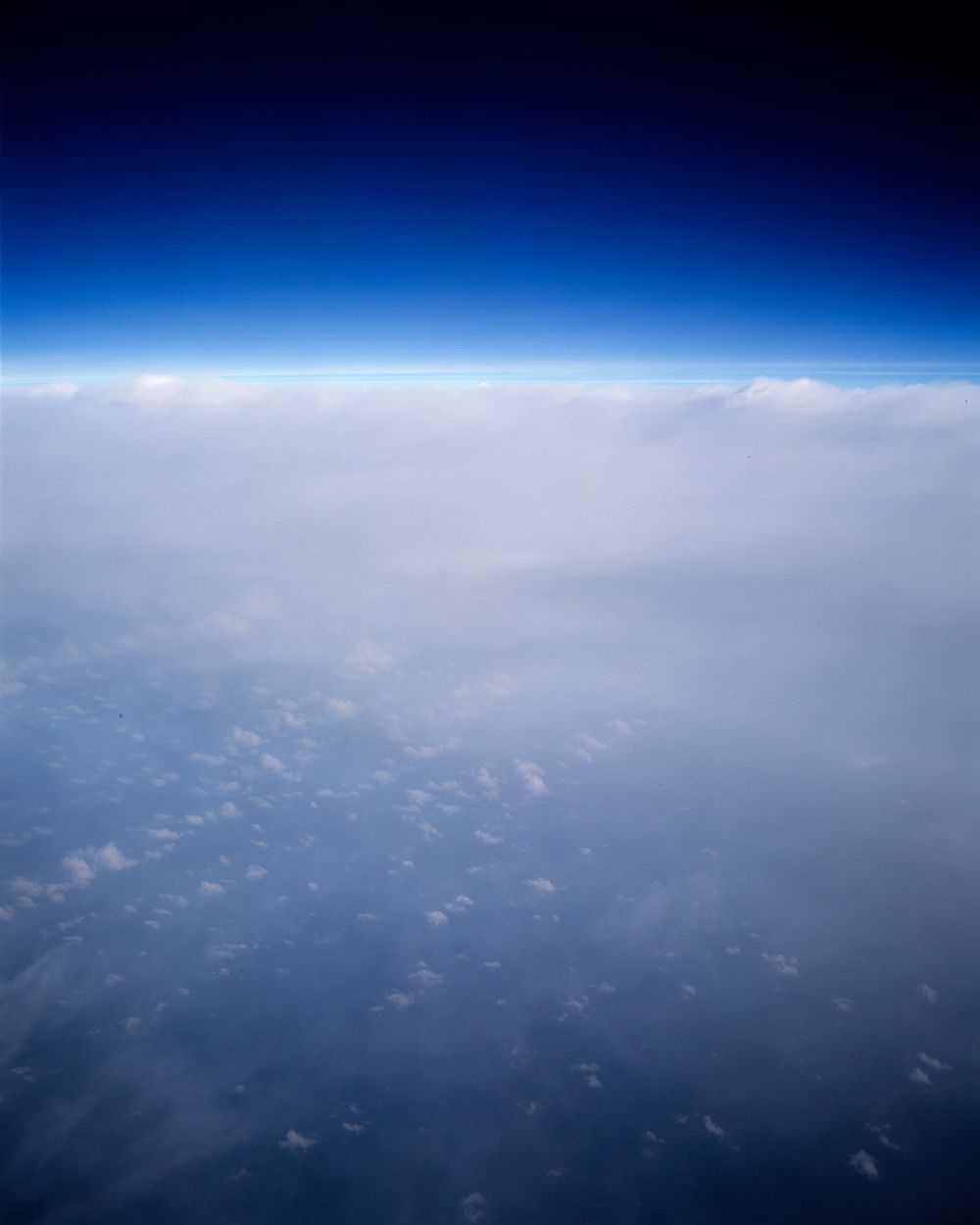 Aerial view of Earth's curvature showing the thin blue atmosphere against dark space.