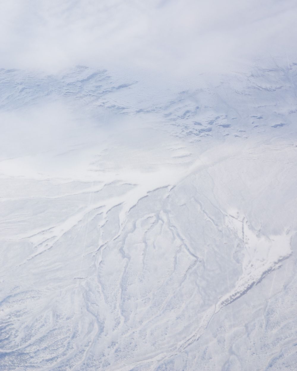 Snow-covered mountain slopes create abstract patterns in white winter landscape.
