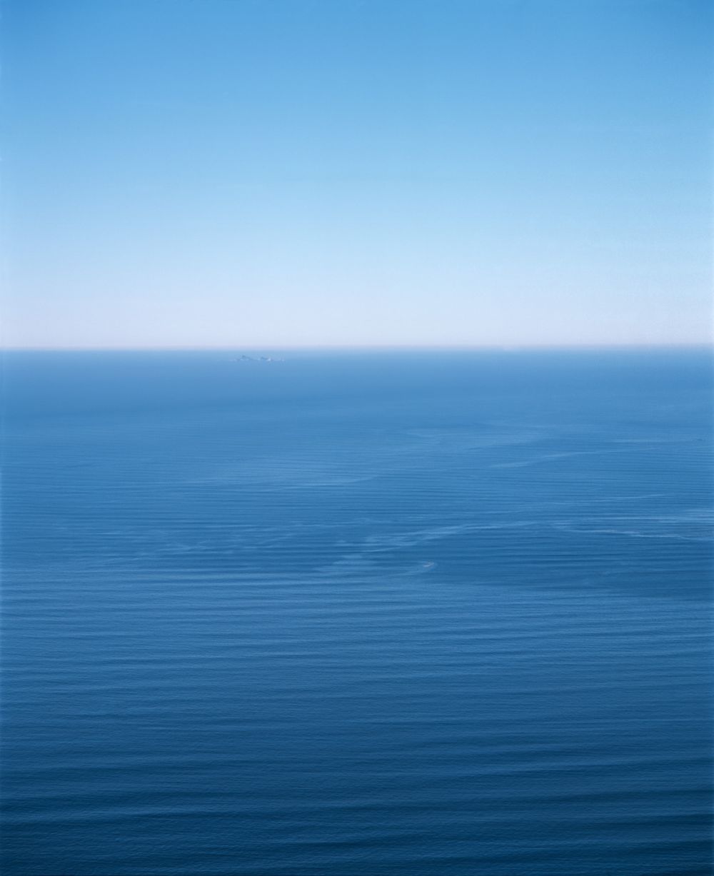 Calm blue ocean extends to the horizon under clear skies creating a serene seascape.