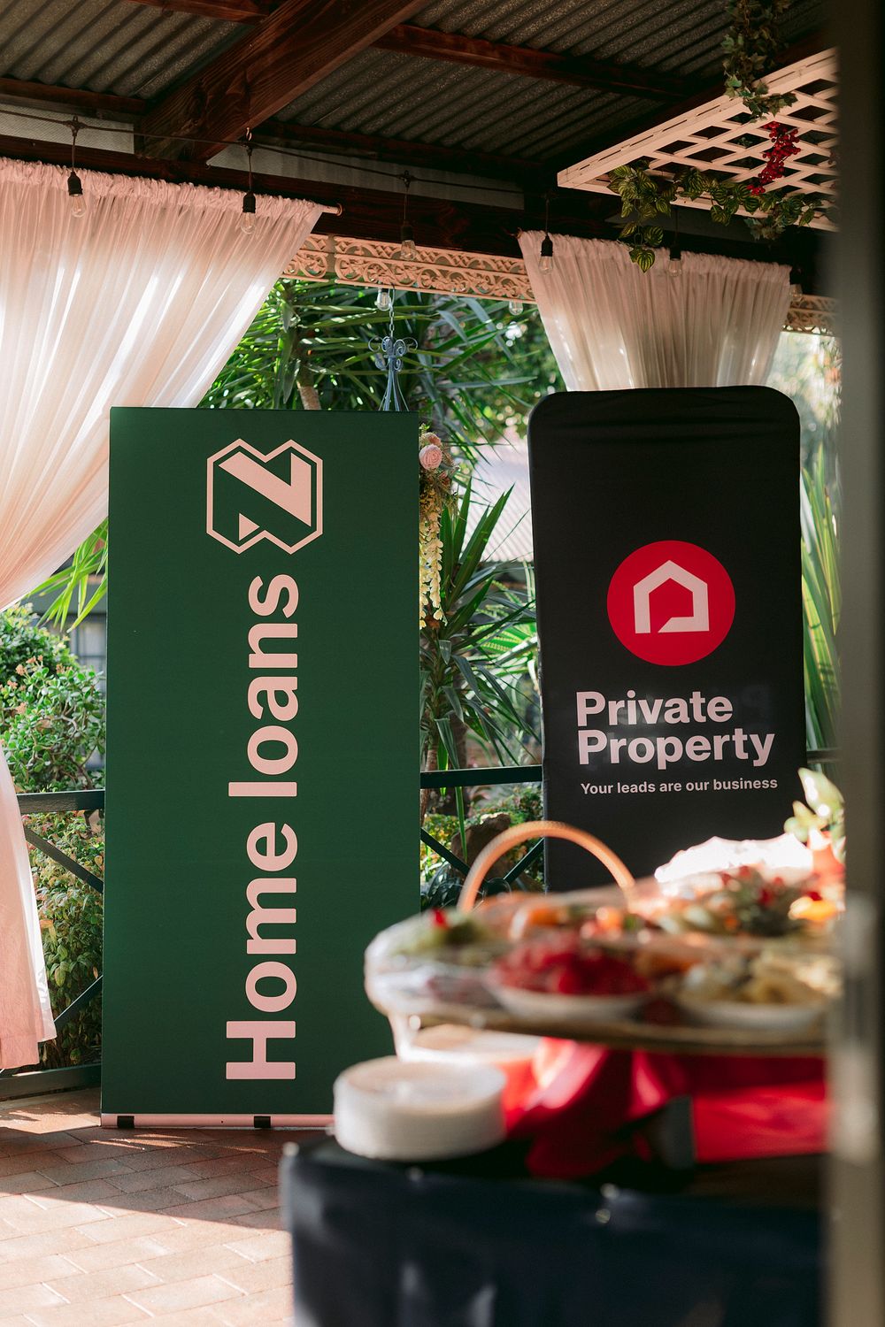 Green Nedbank Home Loans and Private Property branded banners displayed at an outdoor event with lush greenery.