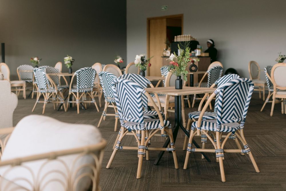 Stylish cafe interior with navy chevron bistro chairs, wooden tables, and fresh floral centerpieces.