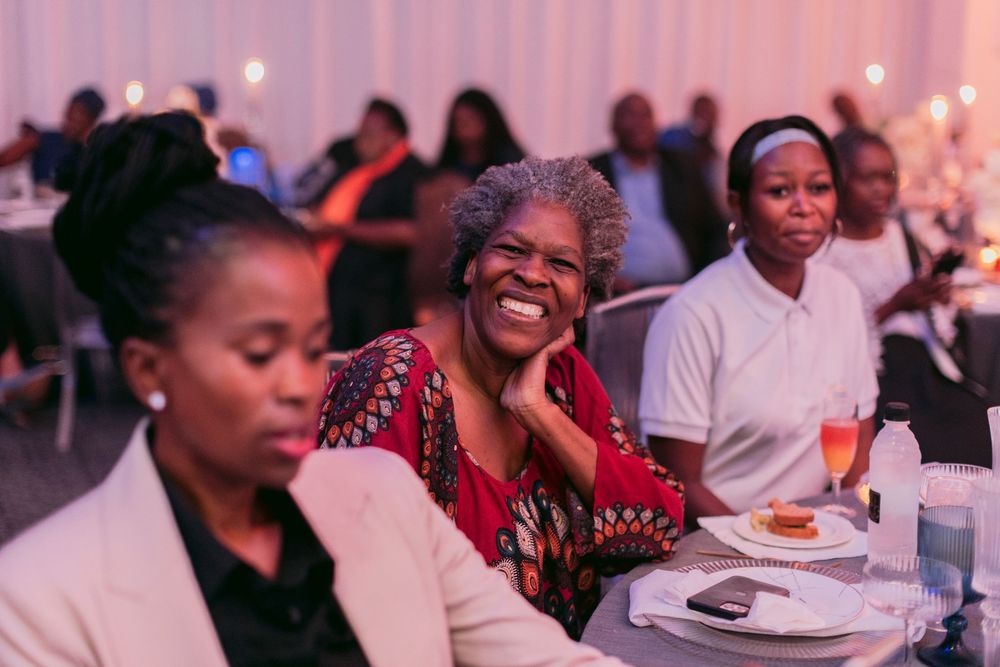 Women laughing and socializing at a formal gala dinner event.